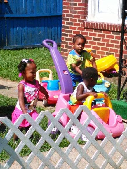 Three children playing with ride-on toys outdoors