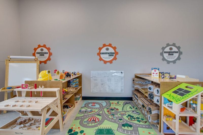 Playroom with shelves of toys, a road map rug, and a whiteboard