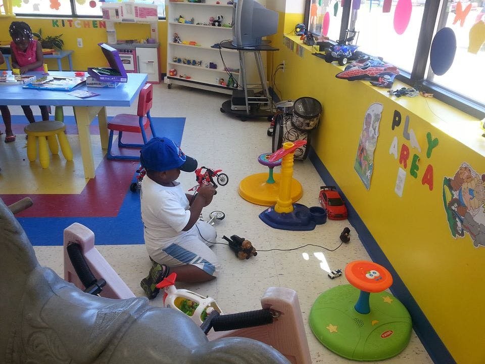 Child kneeling on floor playing with toy motorcycle in a playroom