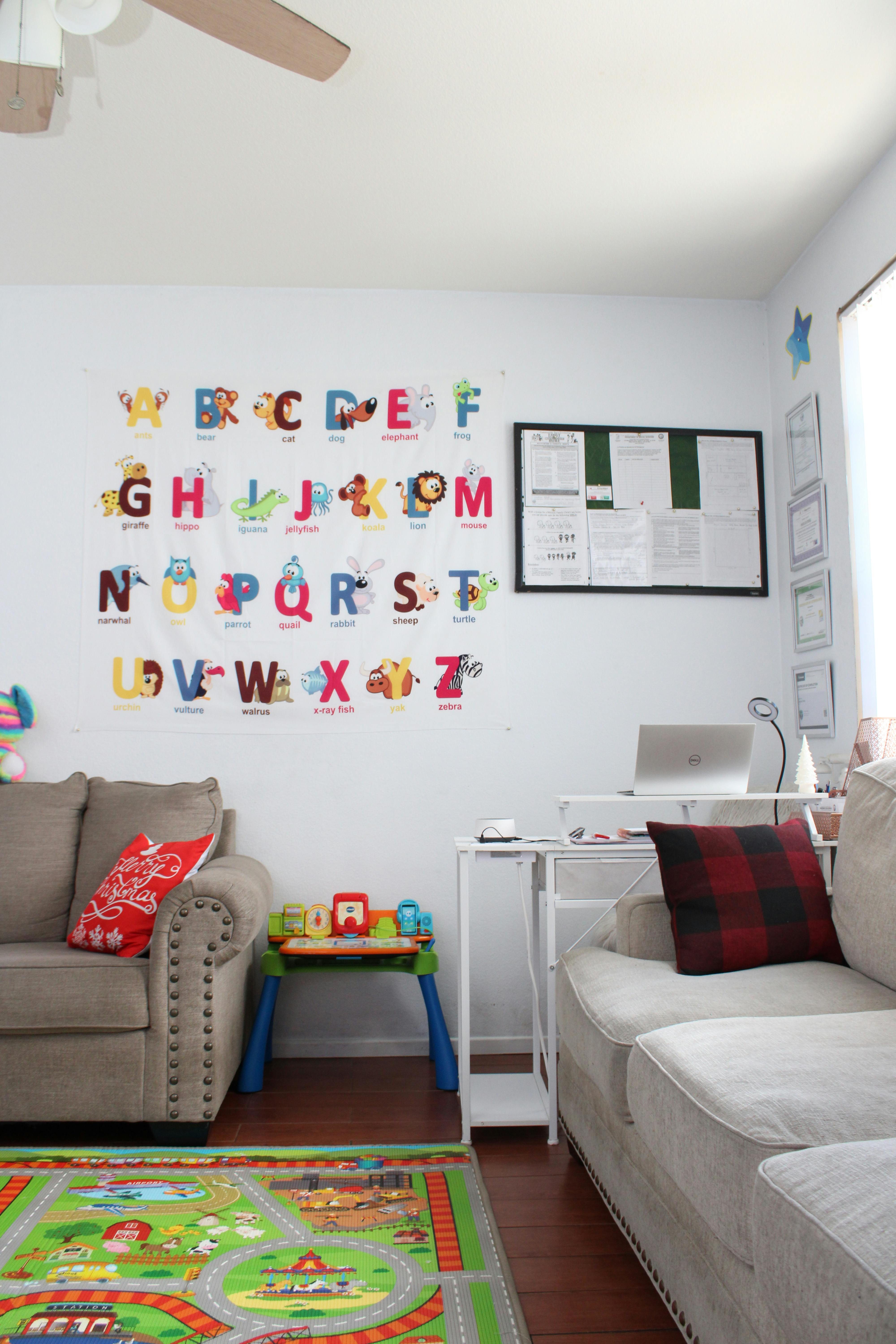 Playroom with an alphabet wall hanging, play mat, and seating
