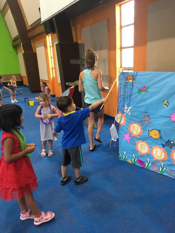 Child playing a fishing game with a person in the background