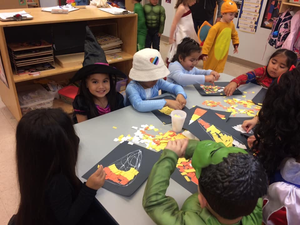 Children in costumes doing crafts at a table
