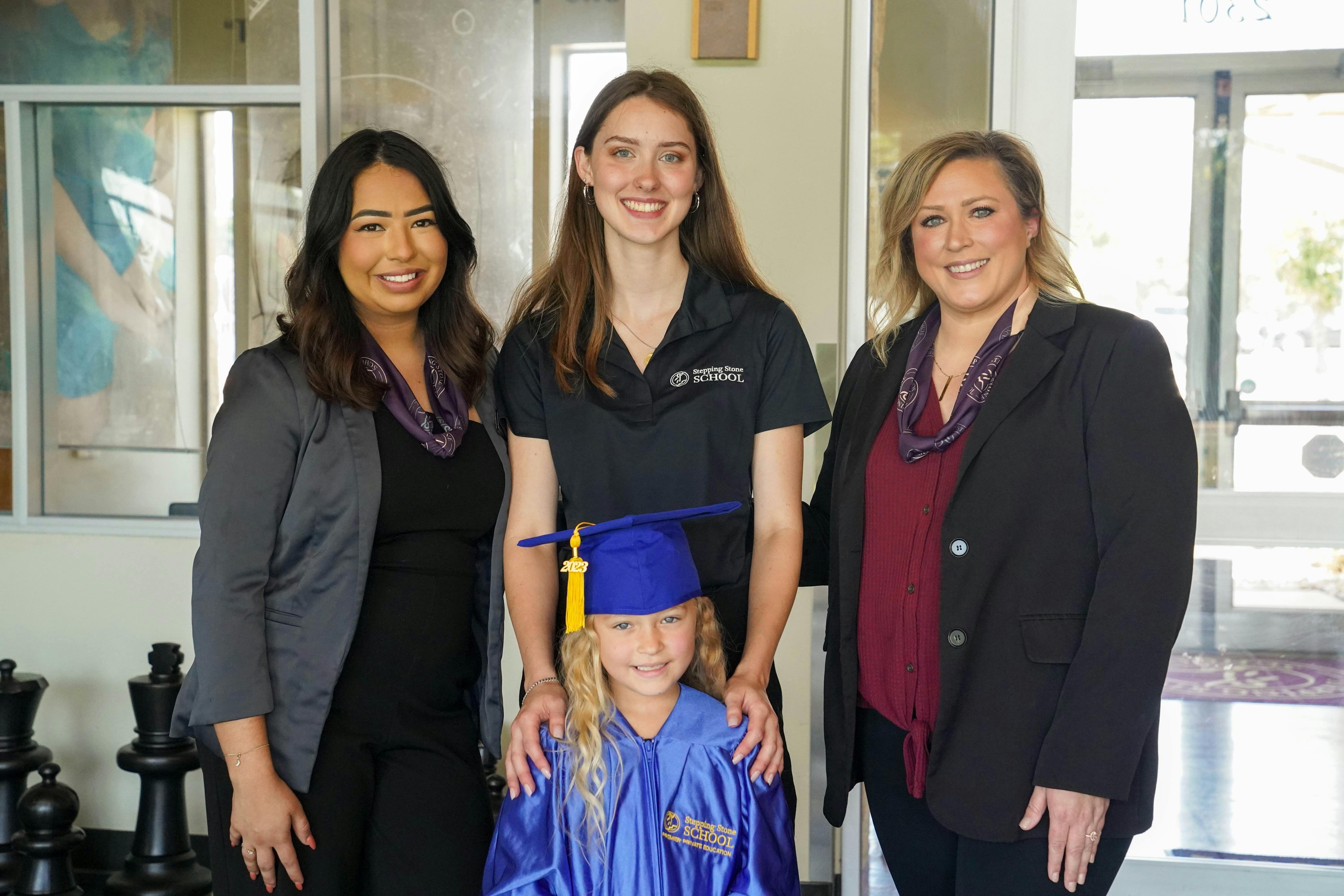 Three people and one child in a graduation gown and cap