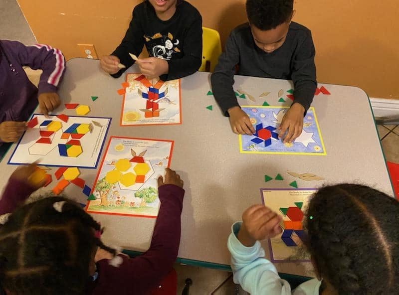 Children at a table playing with colorful geometric shape puzzles