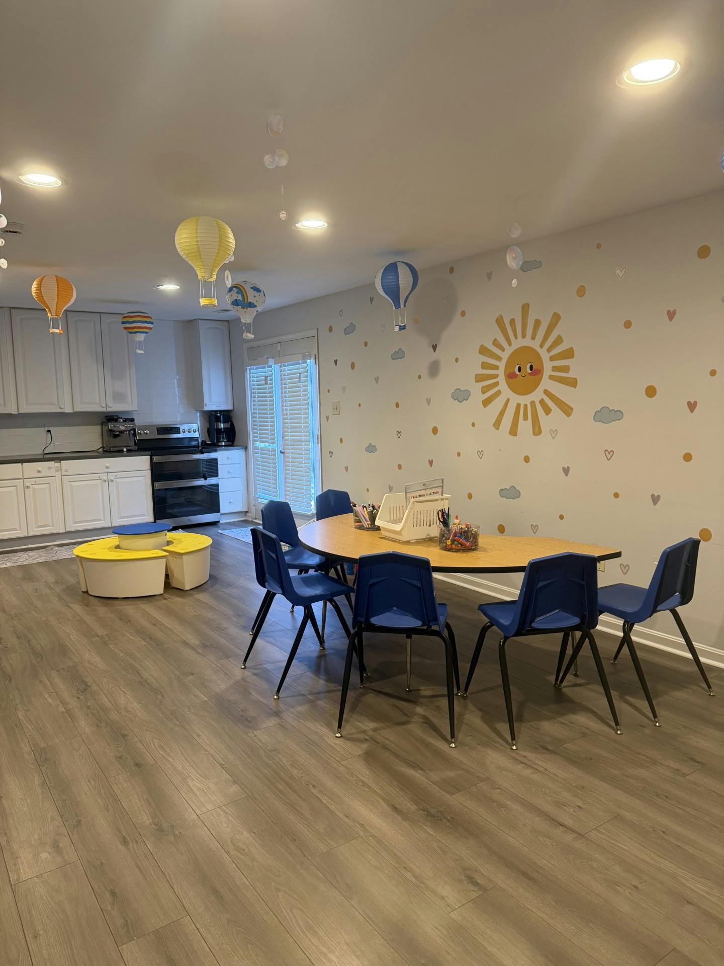 Children's play area with a table and chairs, decorated with hot air balloons and a sun