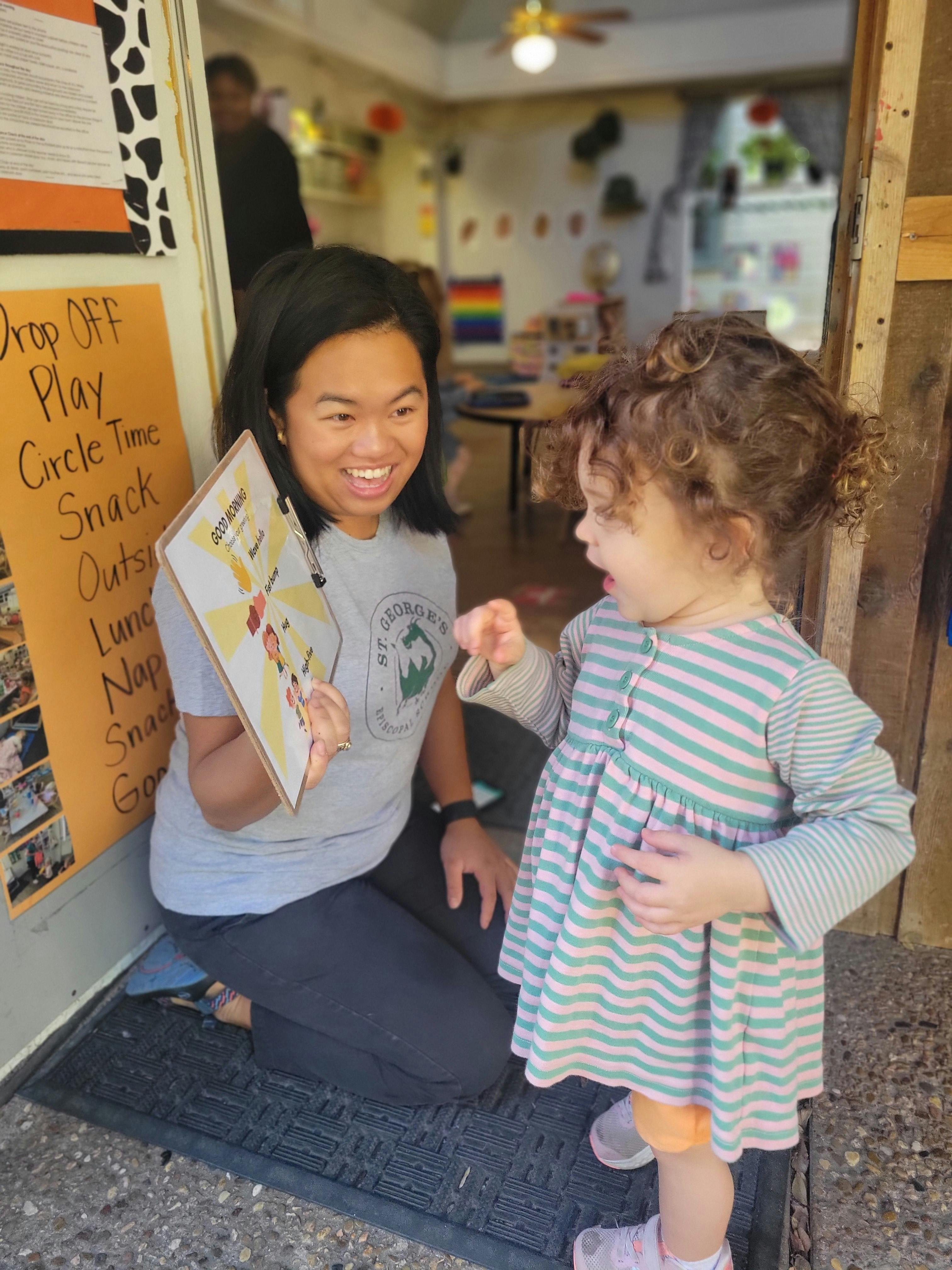 Person kneeling and holding a clipboard, looking at a child