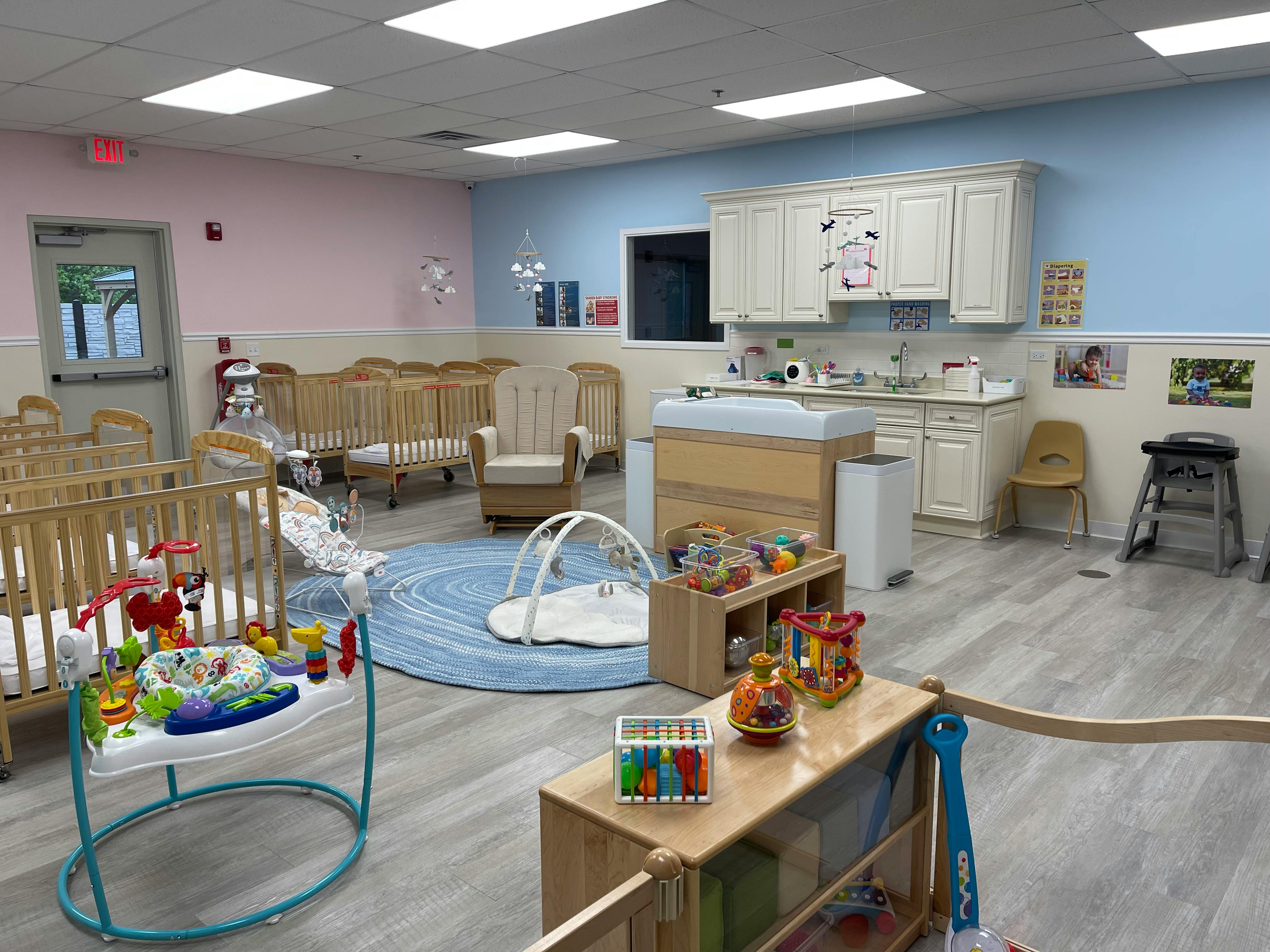 Nursery room with cribs, changing table, and play mat