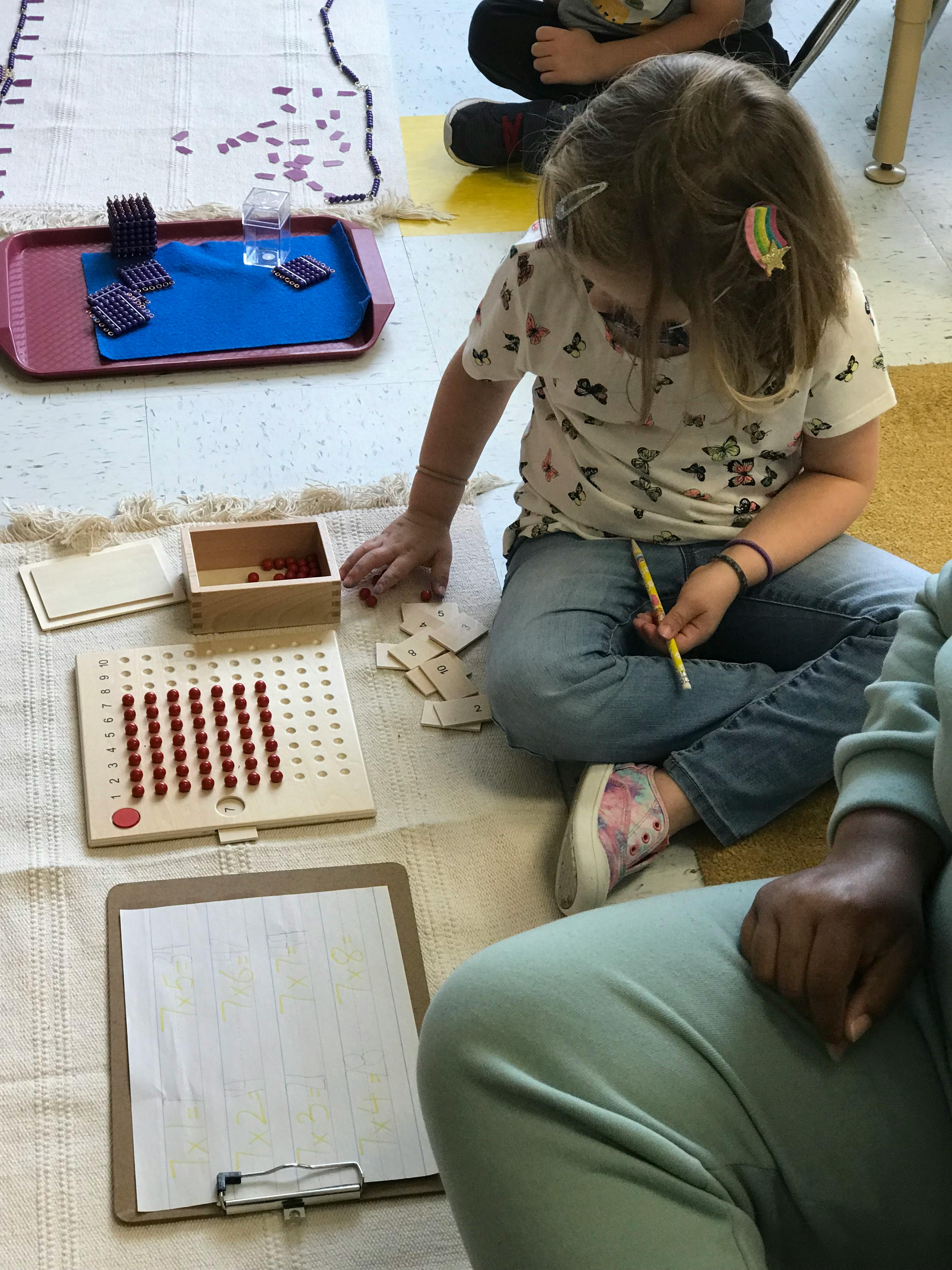Child sitting on floor with educational materials