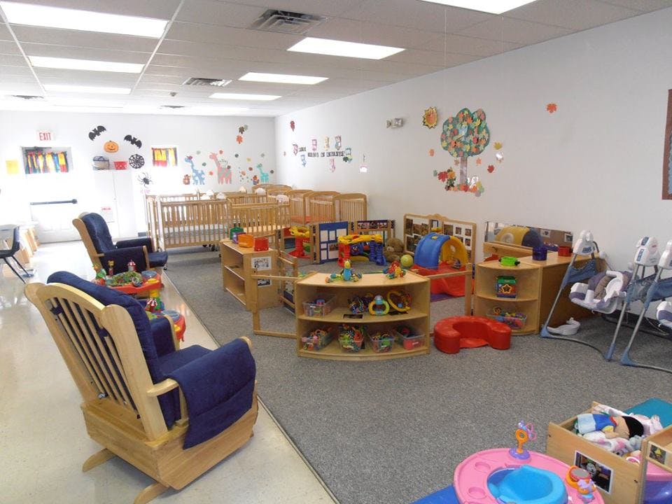 Daycare room with cribs, rocking chairs, and toys