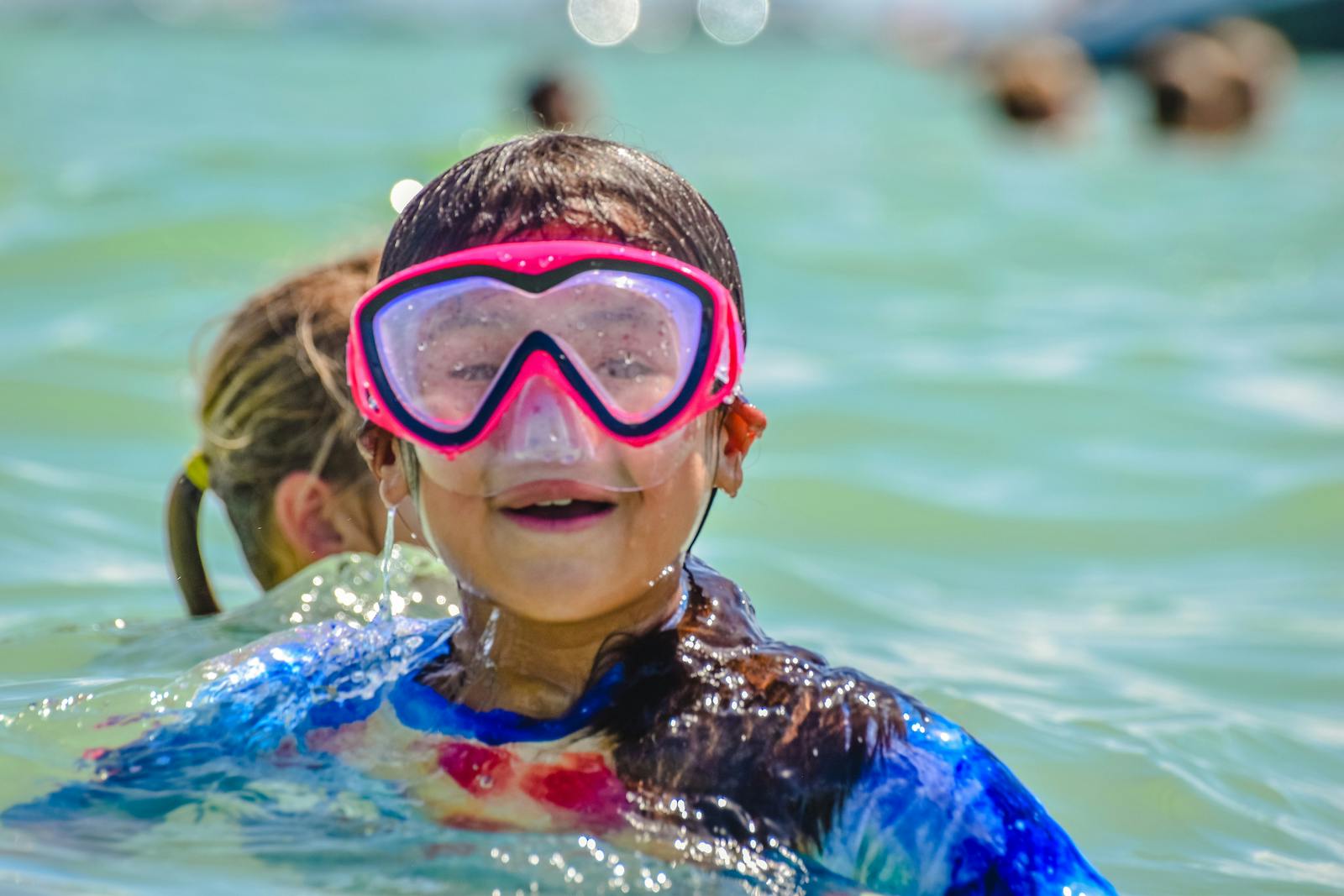 Child wearing a pink snorkel mask in water