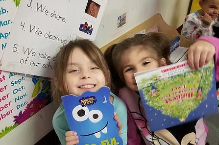 Two children holding up books