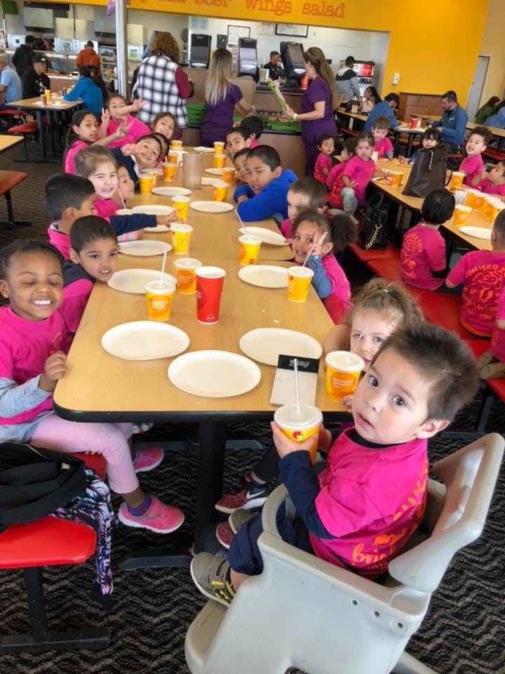 Children sitting at tables with drinks and empty plates