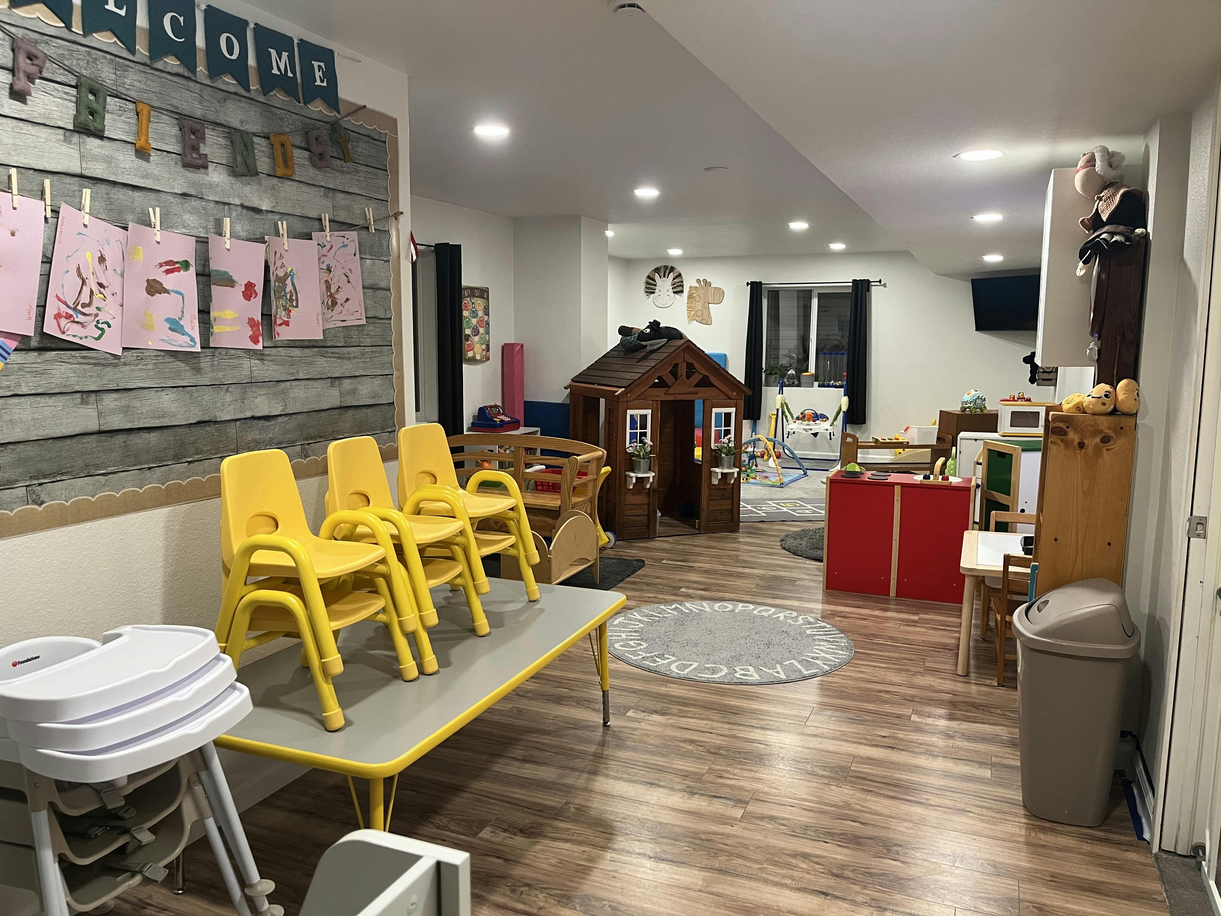 Playroom with children's furniture, a toy playhouse, and wall art