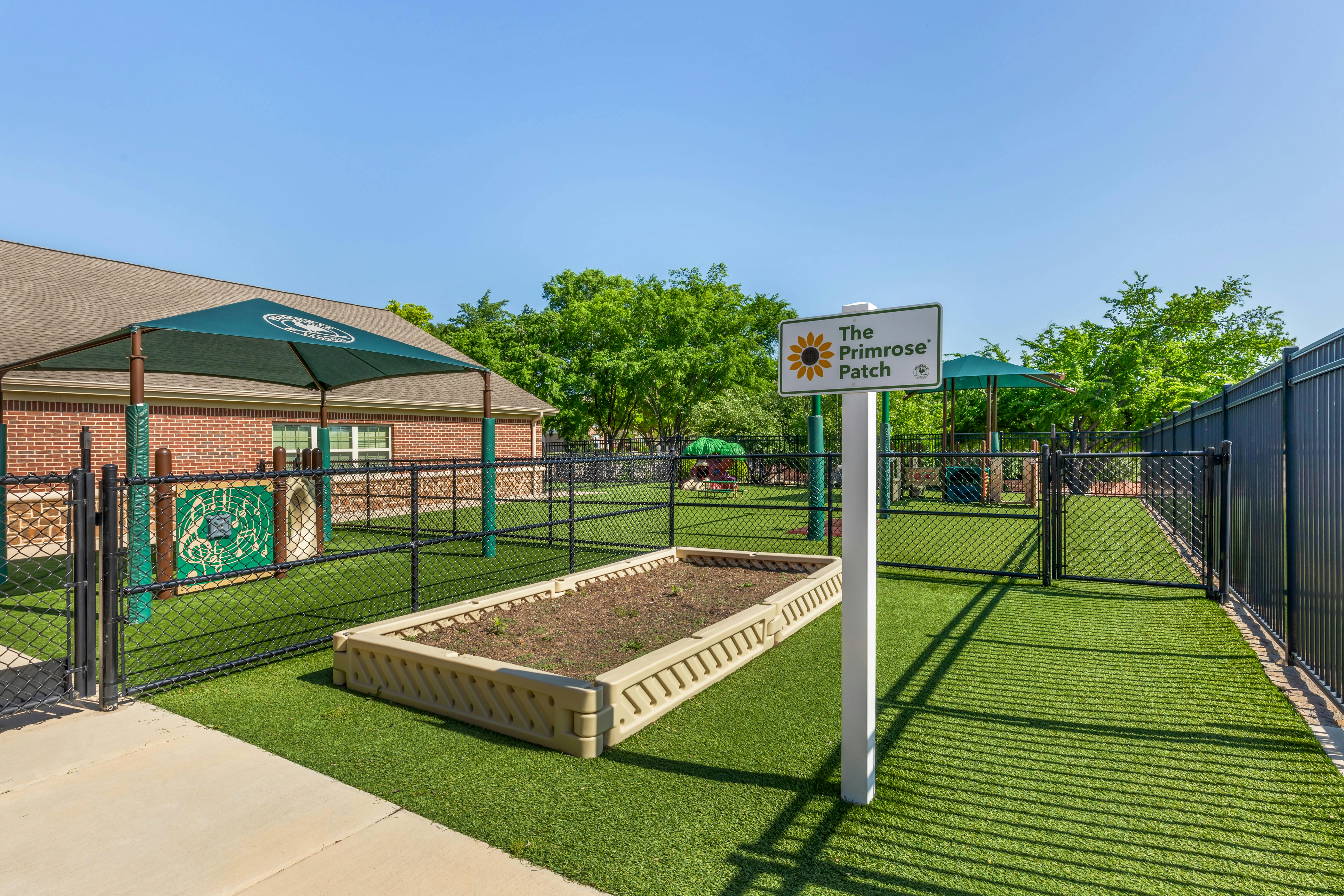 Raised garden bed and playground area with artificial turf, fenced off