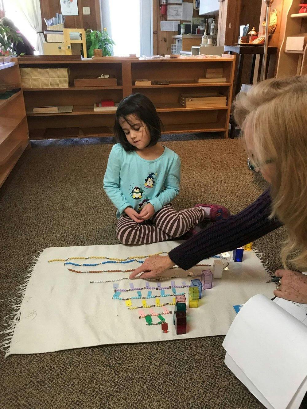 Child and person on floor with learning materials