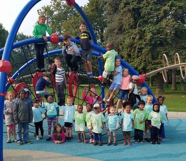 Many children playing on a large climbing structure at a playground