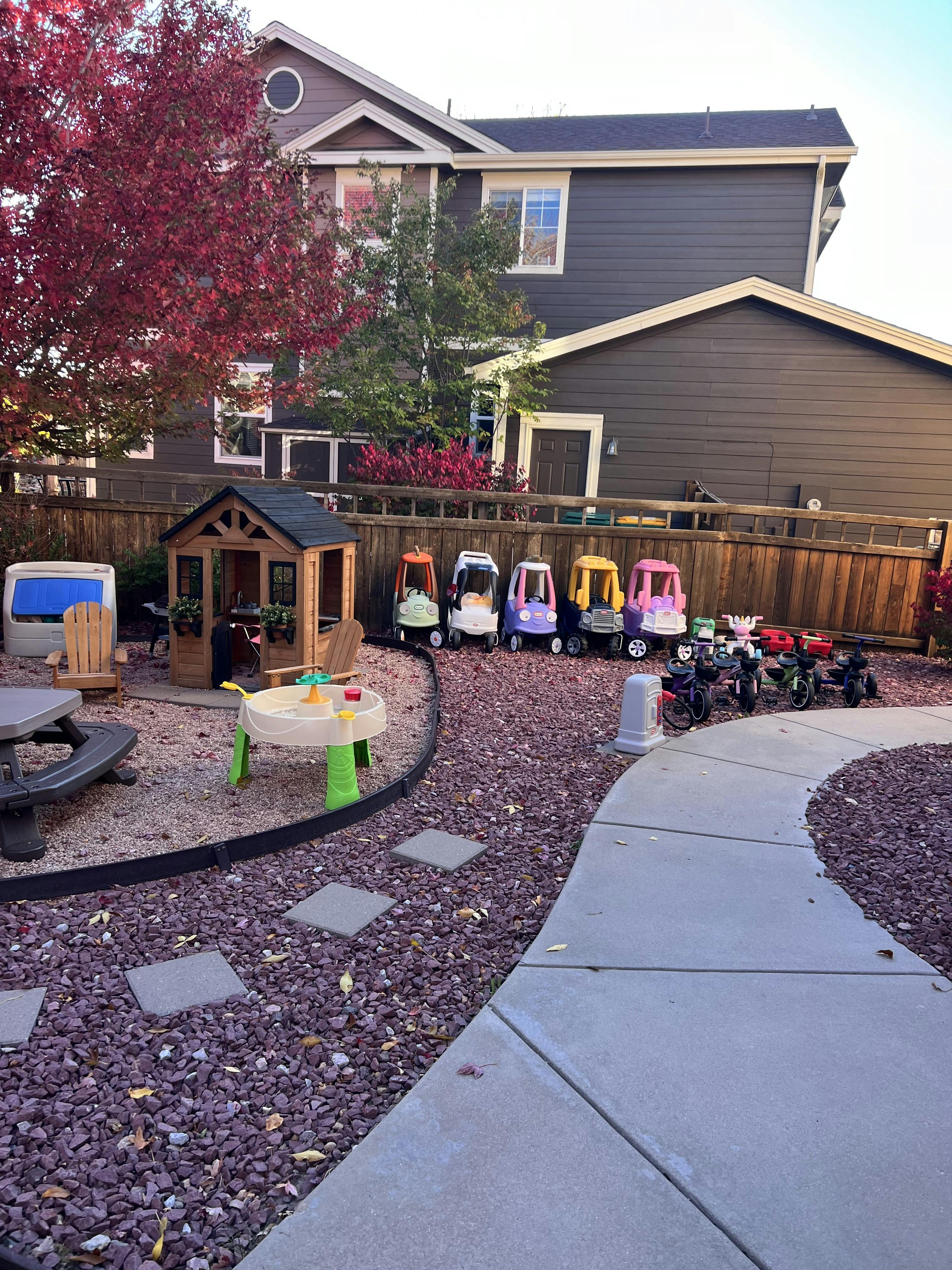 Outdoor play area with toy cars, playhouse, and sand table