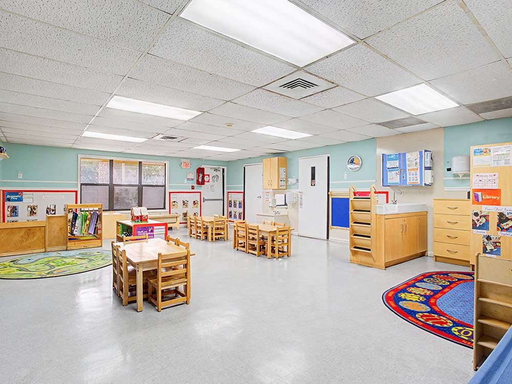 Empty preschool classroom with small tables and chairs