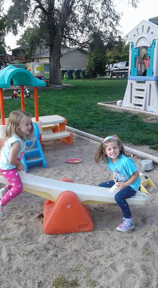 Two children playing on a seesaw in a sandbox