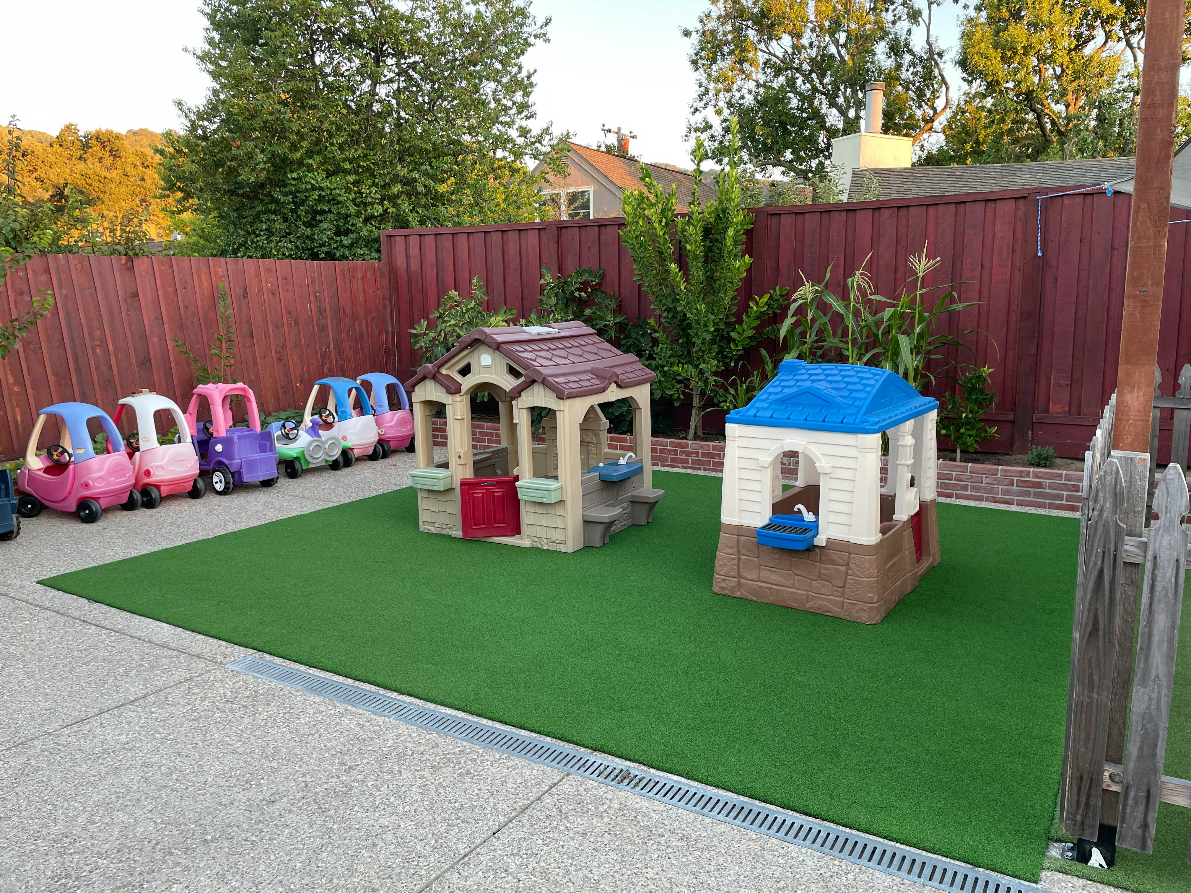 Playground with toy cars and two playhouses on artificial turf