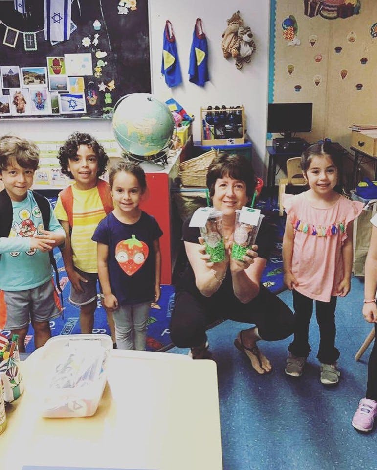 Adult and children holding up crafts in a classroom