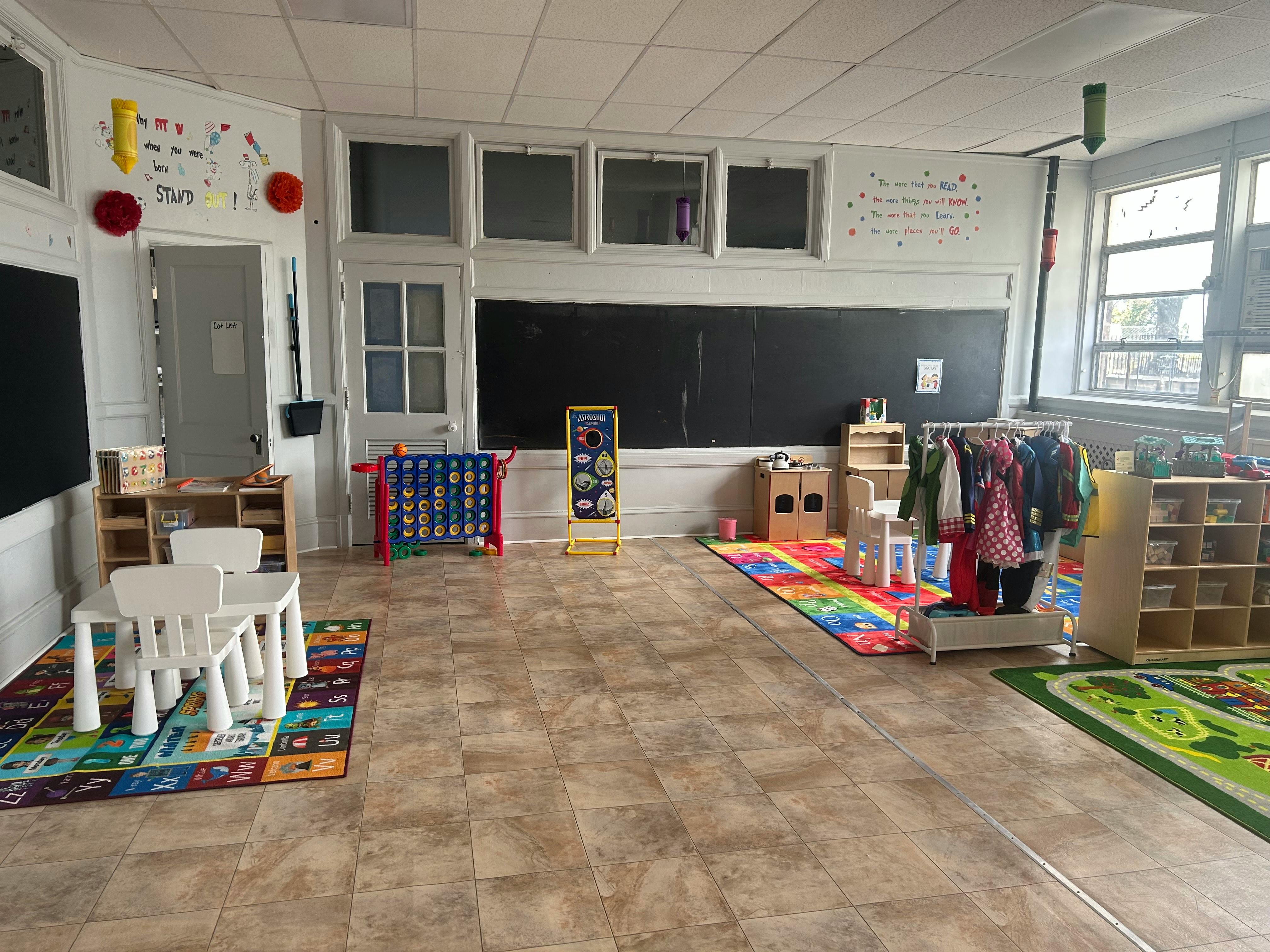 An empty early childhood classroom with a chalkboard and child-sized furniture