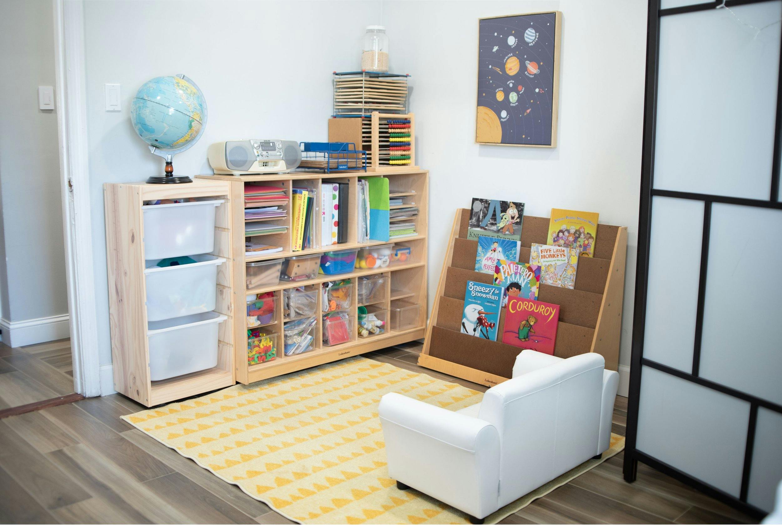 Children's playroom with bookshelves, book display, and small white chair