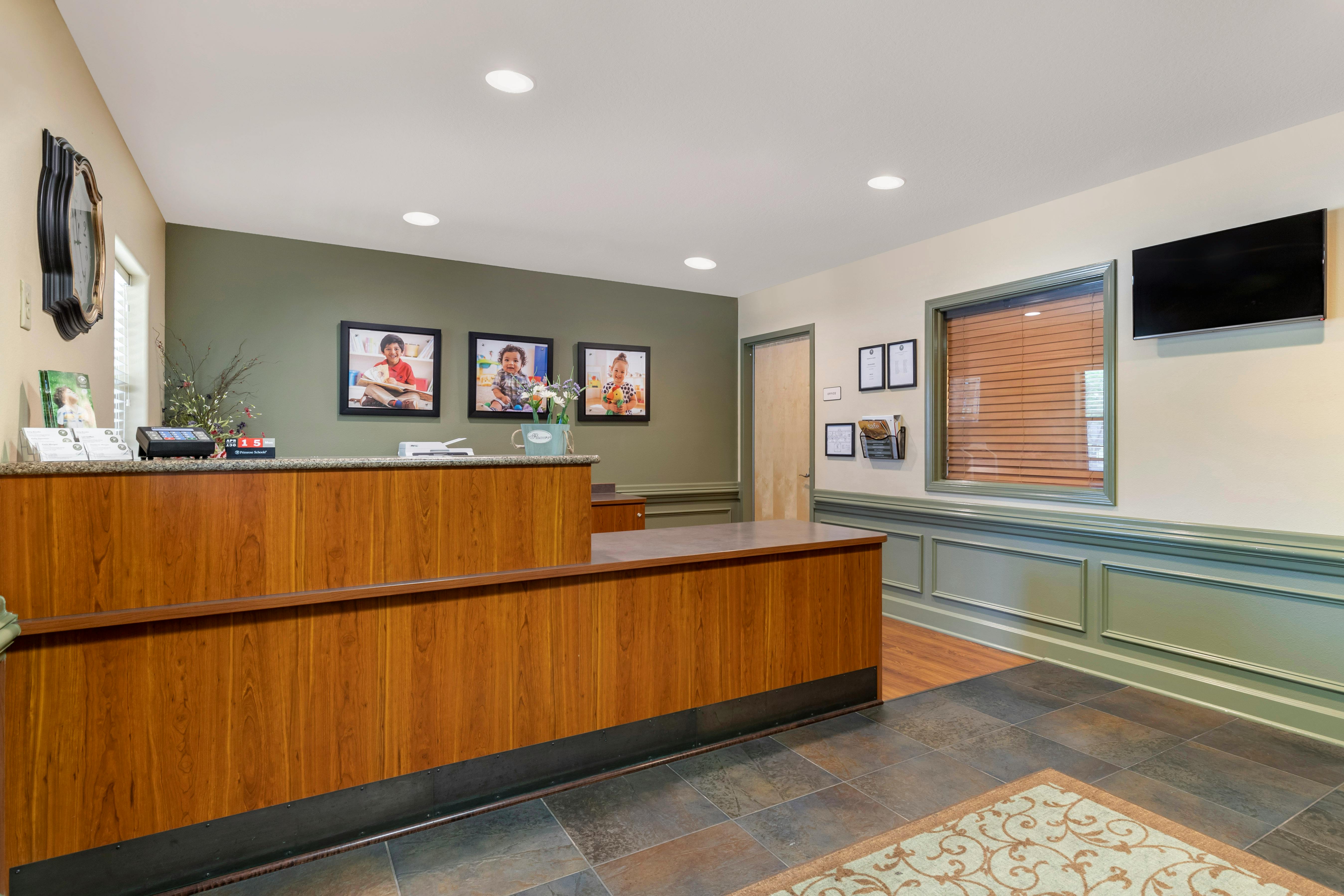 Reception desk with three framed photos of children on the wall
