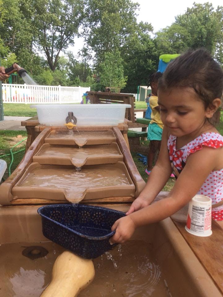 Child playing with a water table and a water flow toy