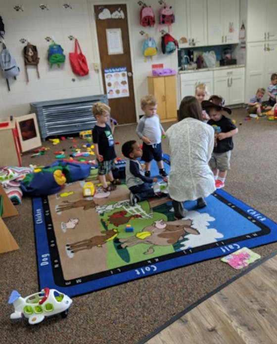 Adult and children gathered around a rug in a classroom