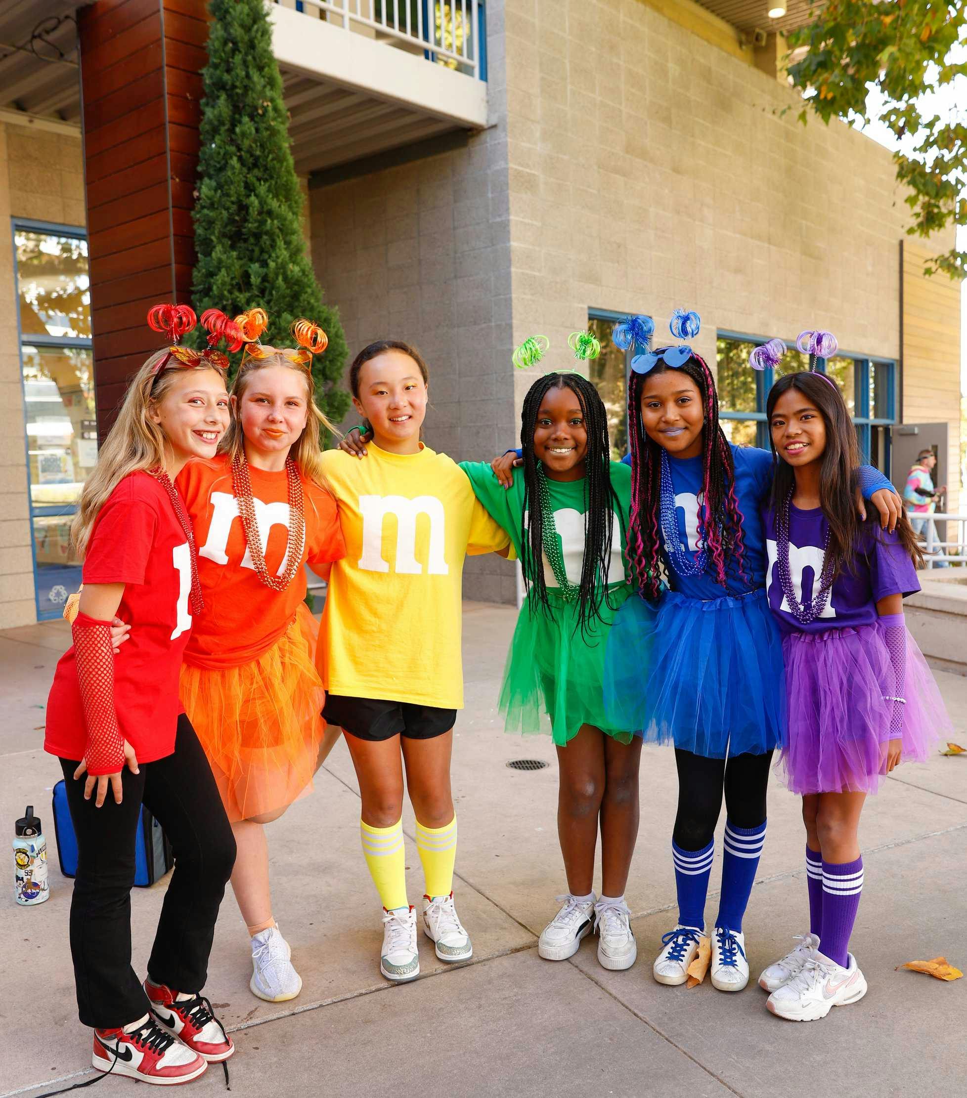 Six children in colorful M&M themed costumes standing together