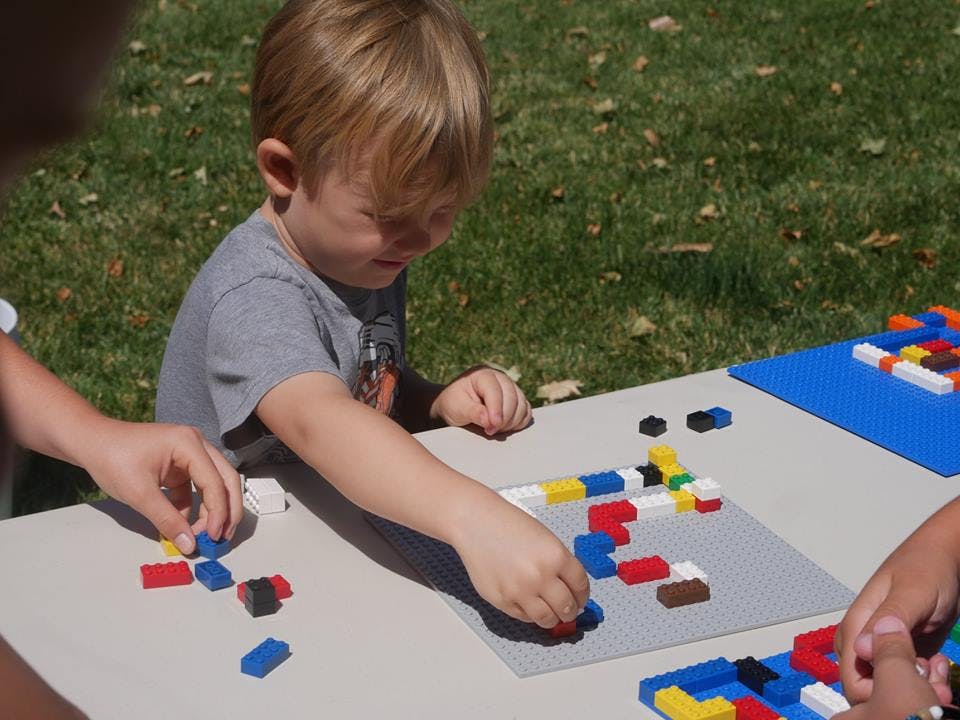 Child playing with colorful building blocks on a table outdoors