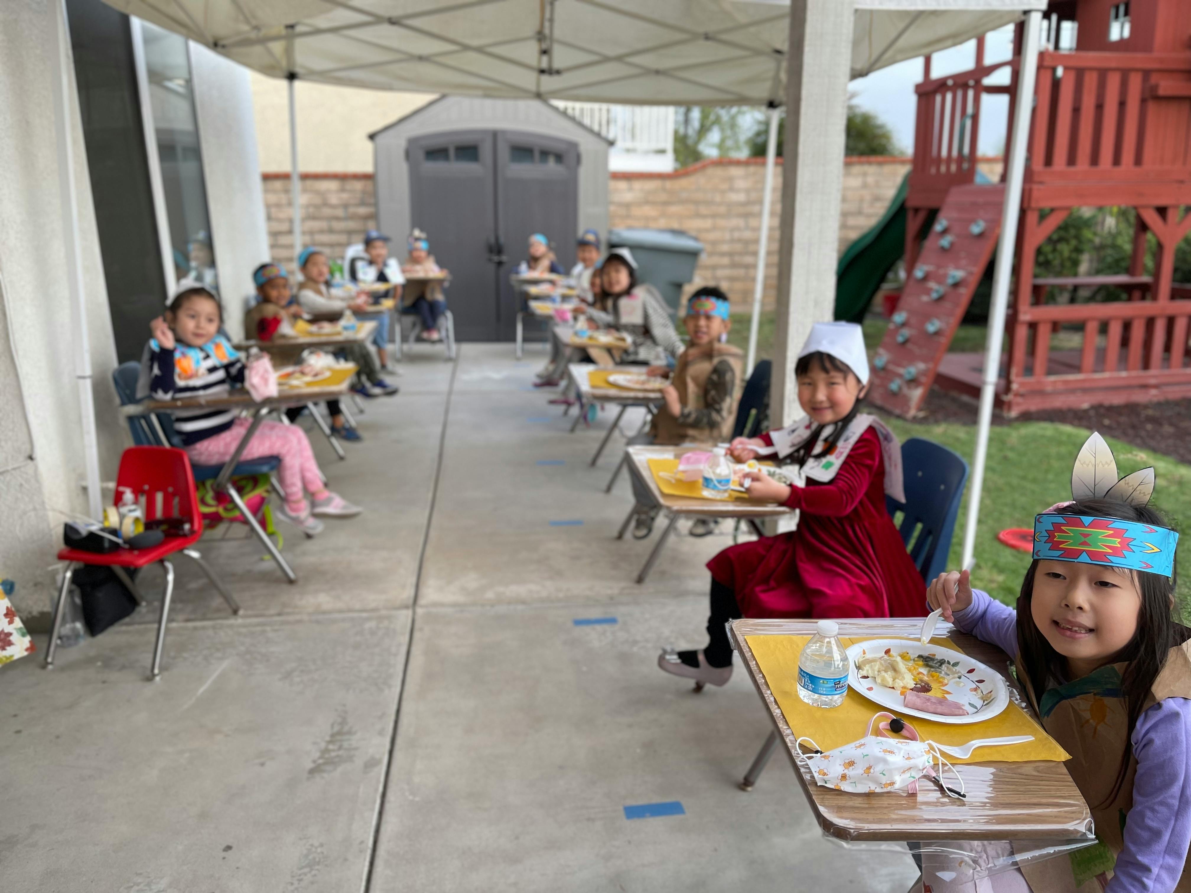 Children sitting at individual desks outdoors