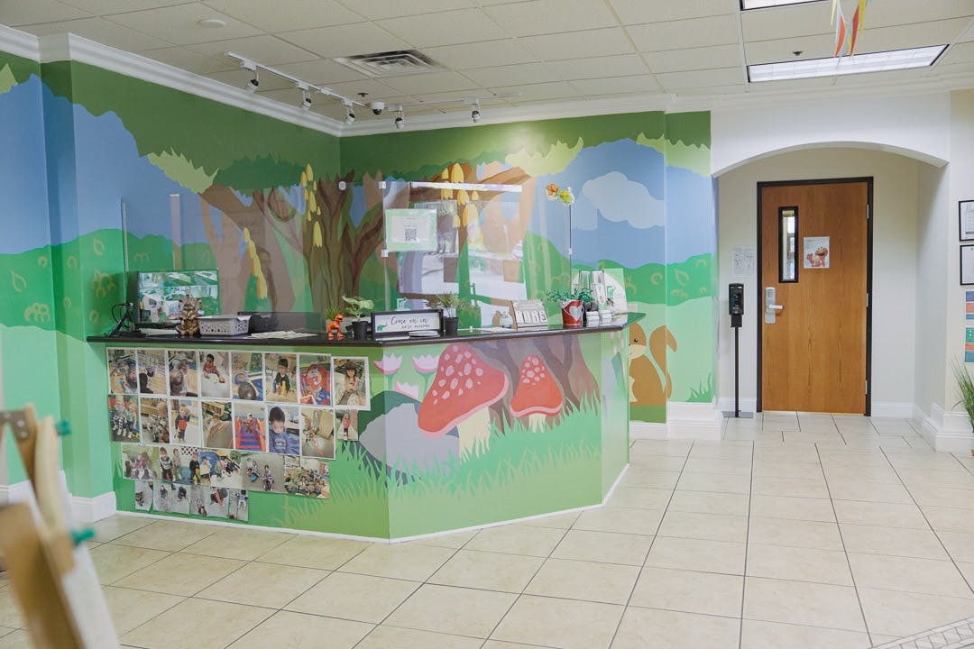 Reception desk with a nature-themed mural and a wooden door