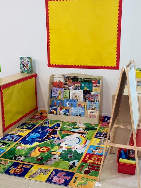 Children's classroom with a colorful rug, book display, and easel