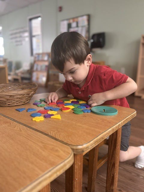 Child playing with colorful plastic shapes at a table