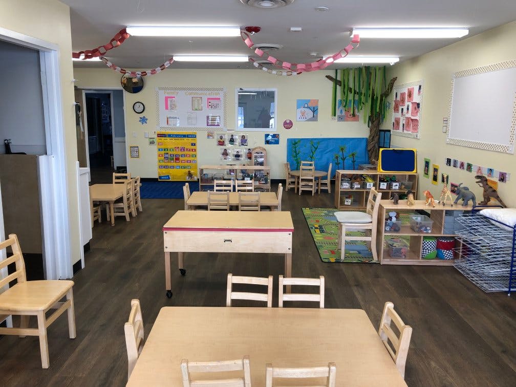 Classroom with small wooden tables and chairs, and decorations