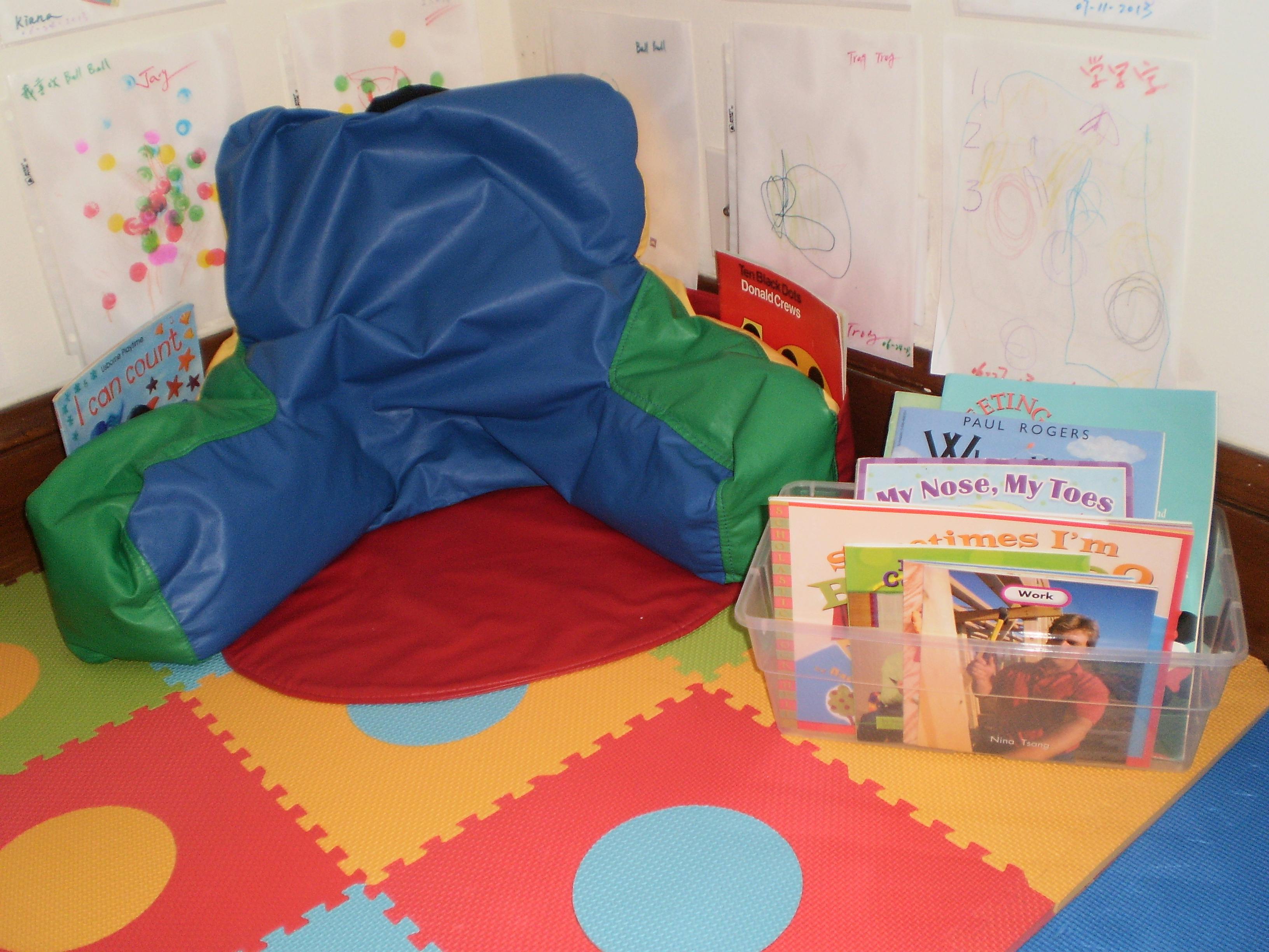 Blue and green beanbag chair on a red mat with books in a classroom