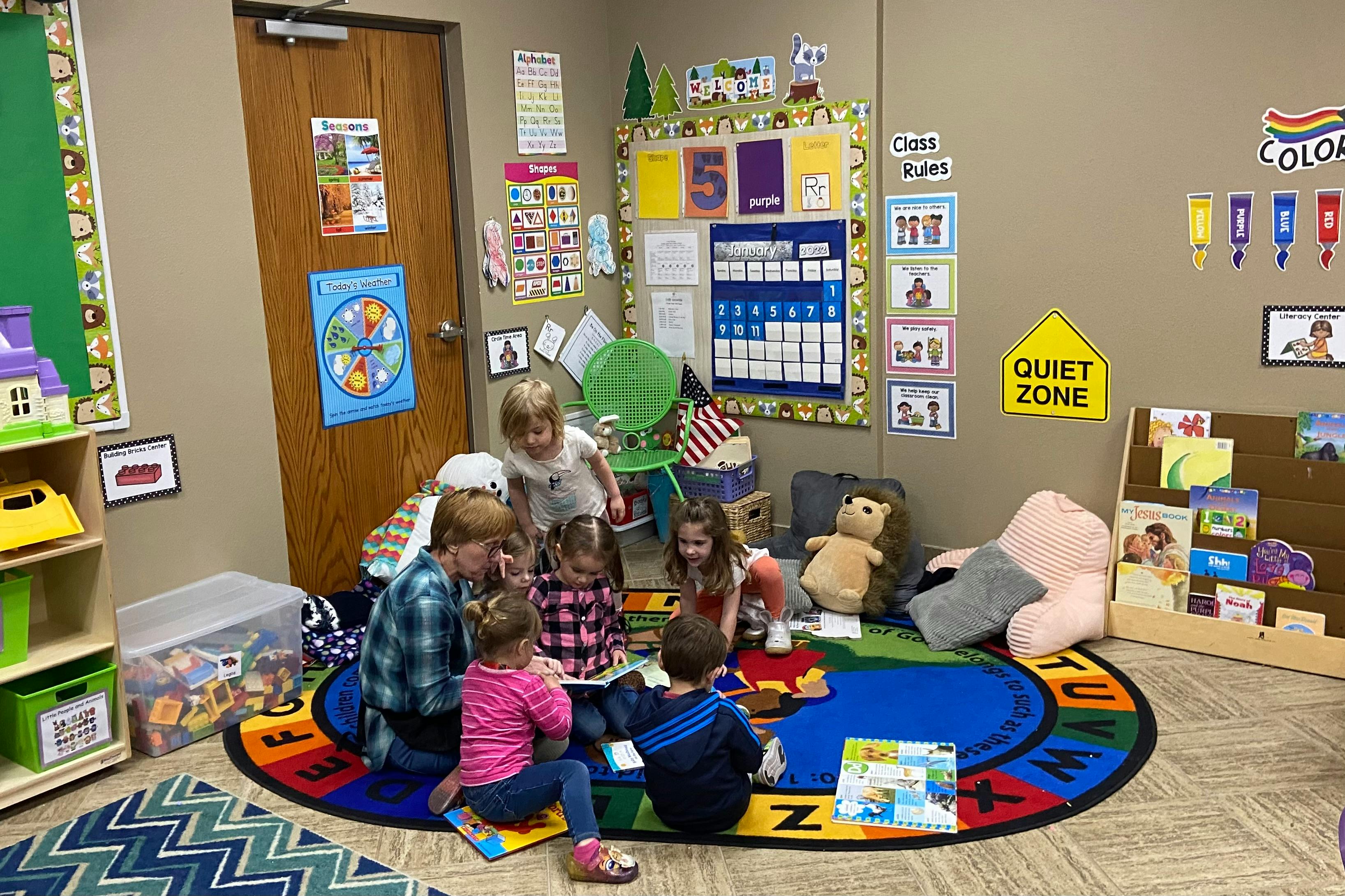 Adult and children reading a book together in a classroom