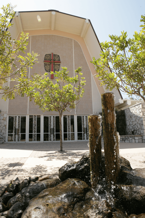 Building with a cross on the facade and a water feature in the foreground