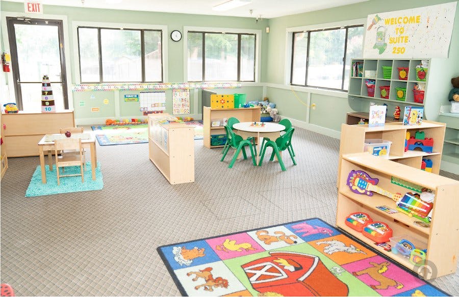 Empty classroom with small tables, chairs, and shelves with toys
