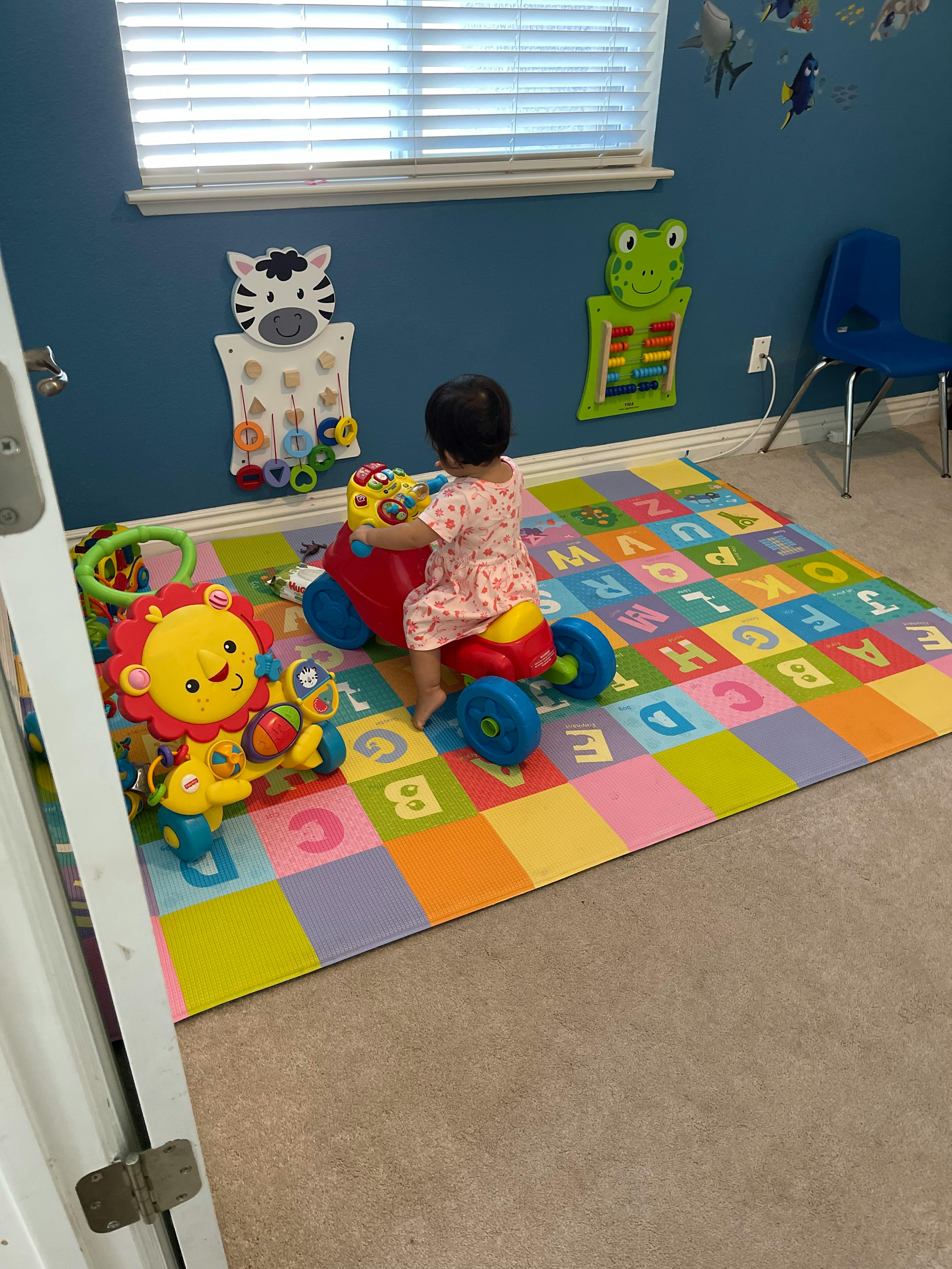 Child on a ride-on toy on an alphabet playmat
