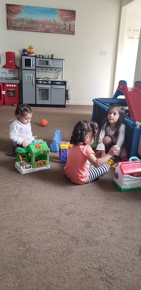 Three children playing with toys on a carpeted floor