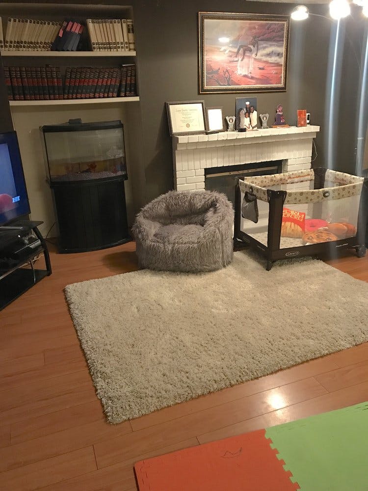 Living room with fireplace, shelves, fish tank, bean bag chair, and playpen