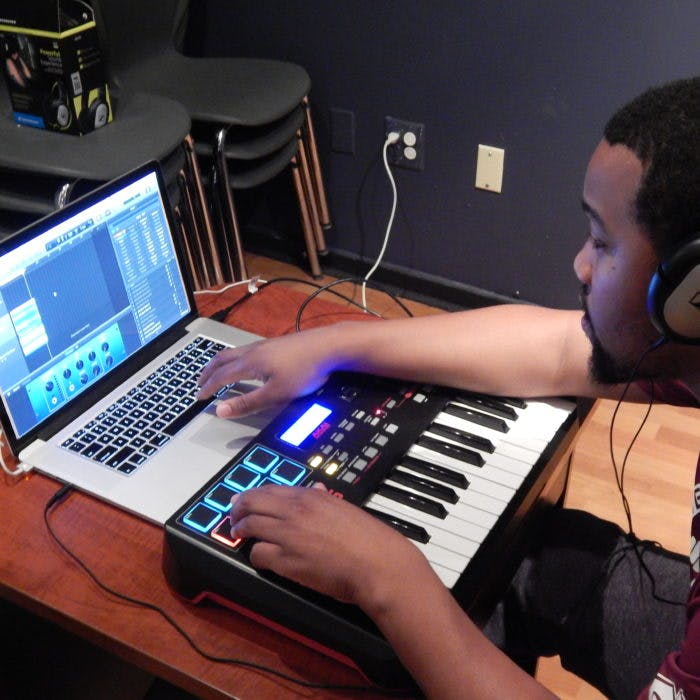 Person wearing headphones using a laptop and a MIDI keyboard