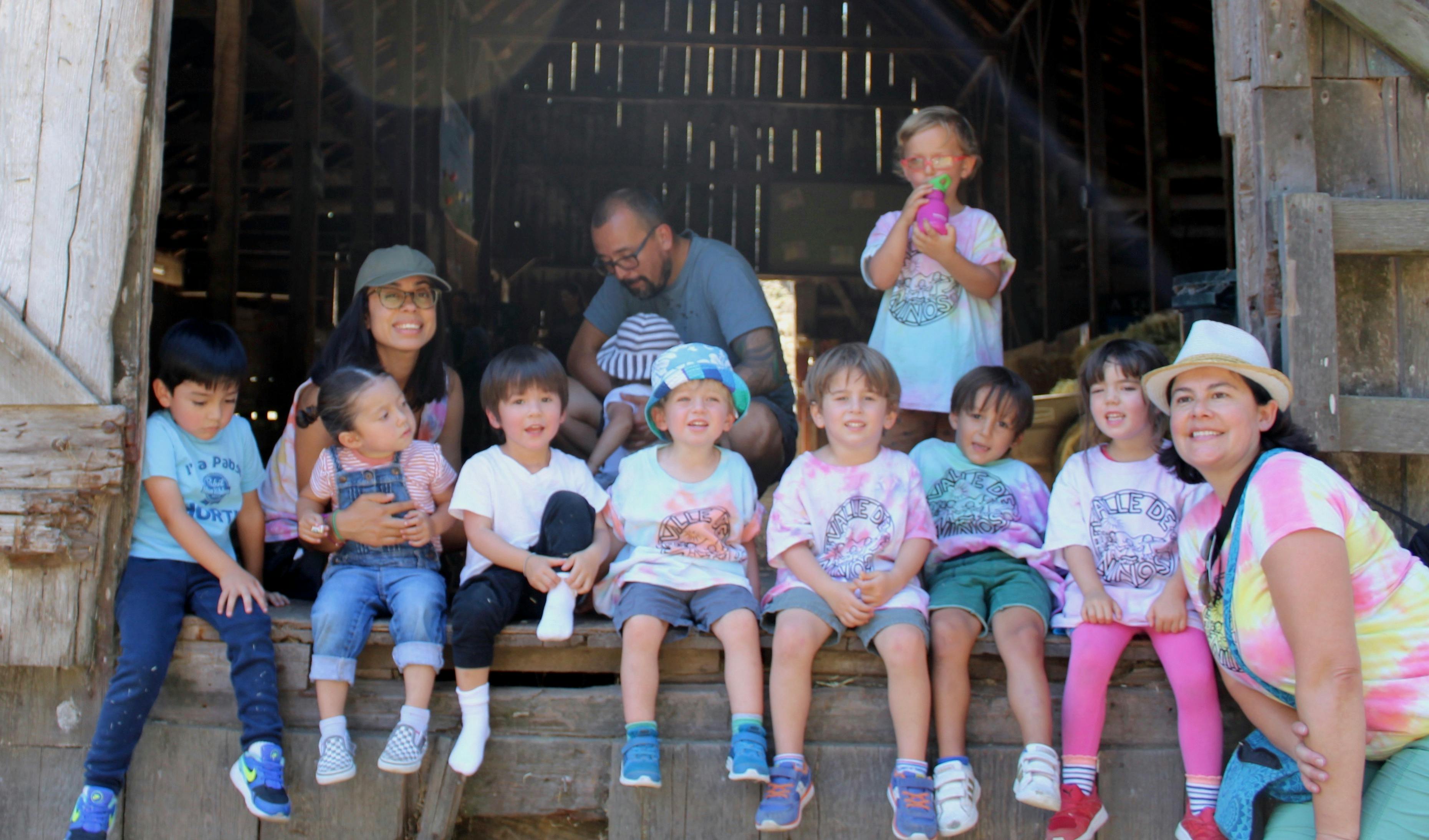 Group of adults and children sitting on a wooden porch
