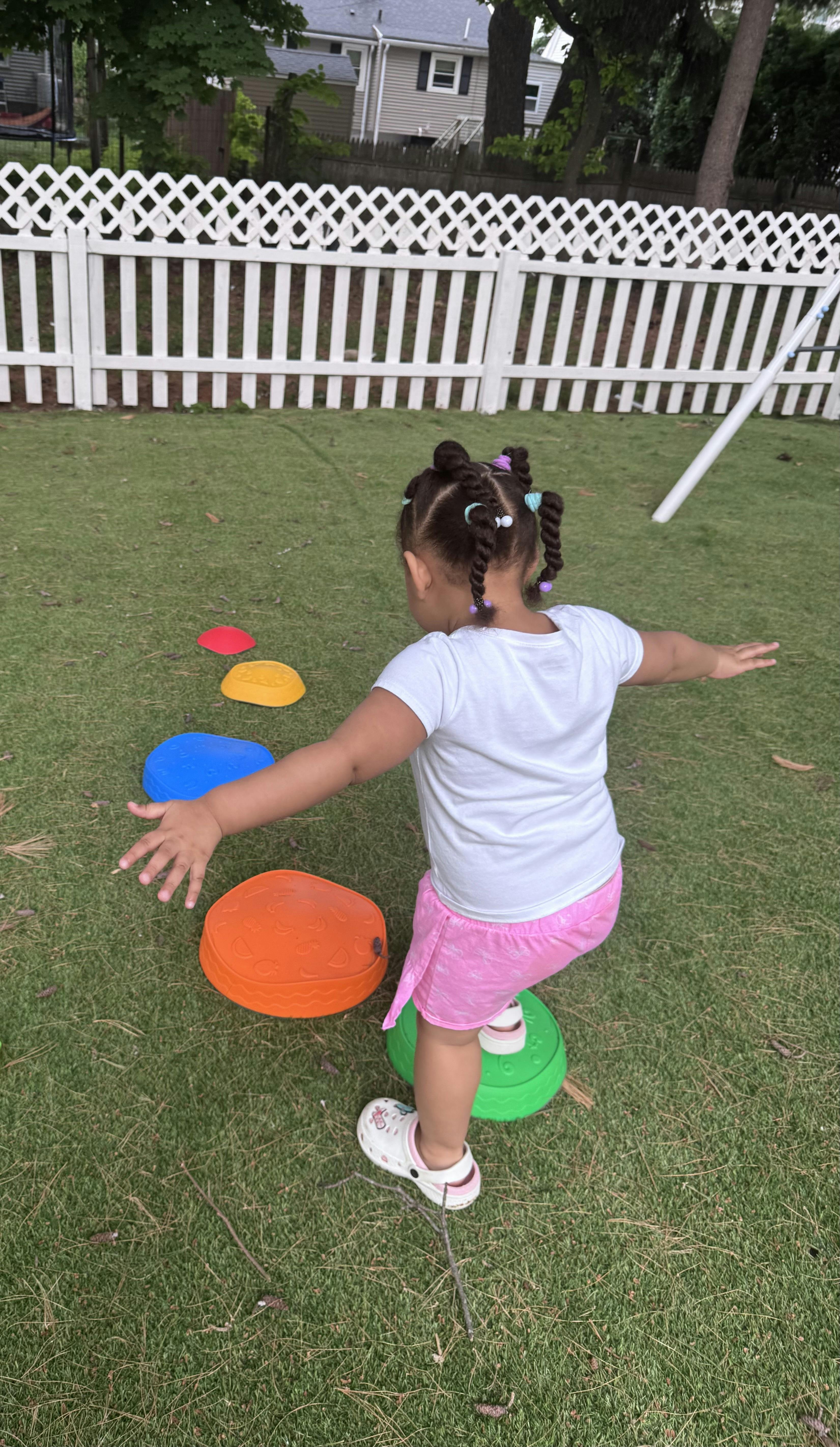Child balancing on colorful stepping stones on a lawn