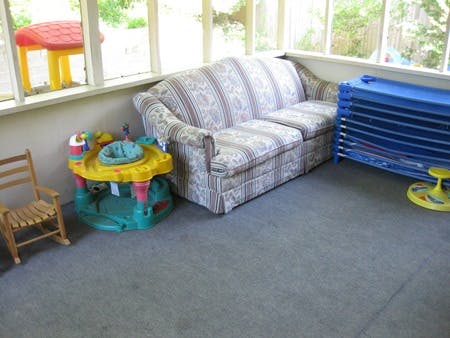 Sofa, child's activity center, and stacked blue cots in a room