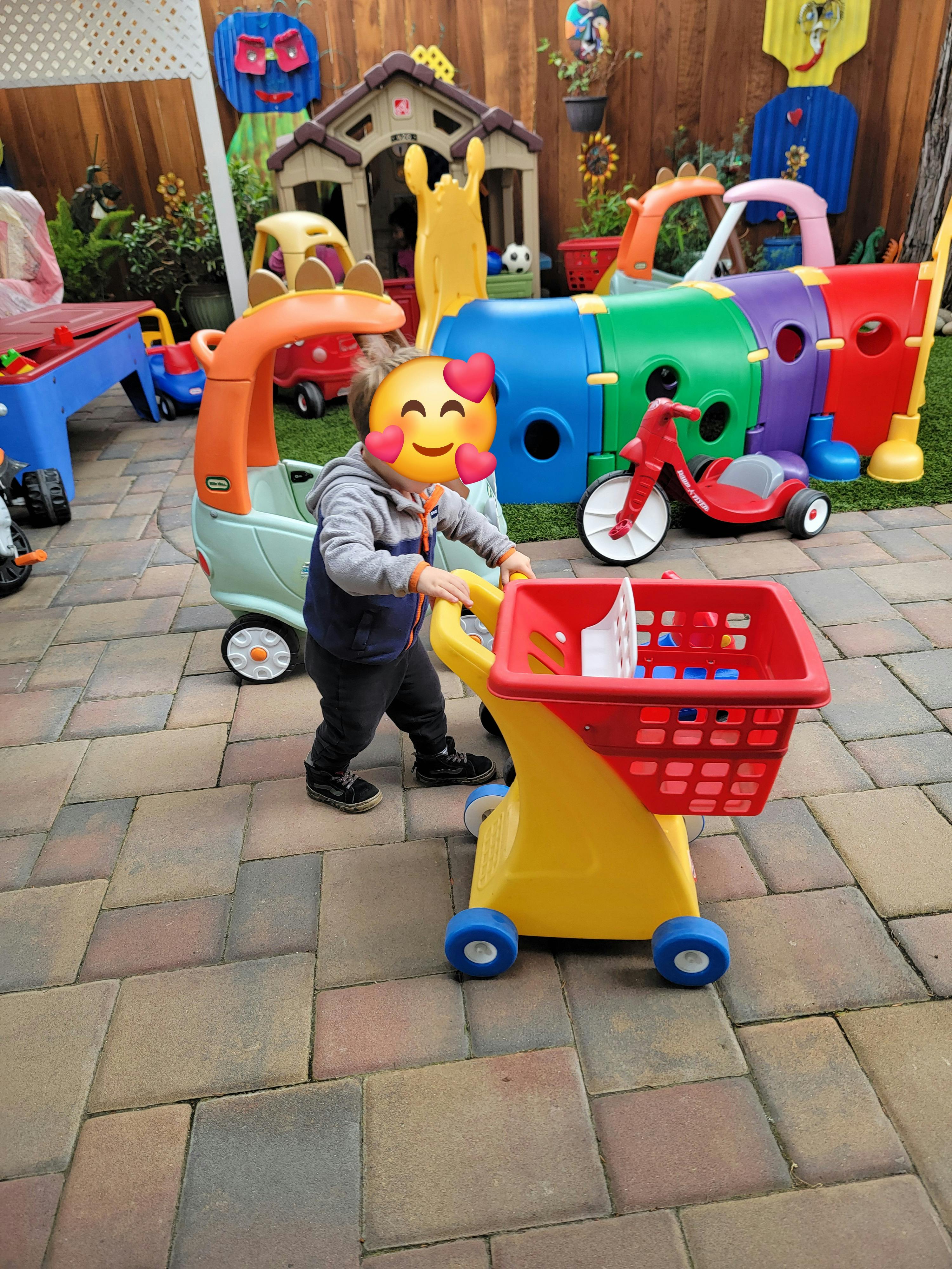 Child pushing a toy shopping cart outdoors