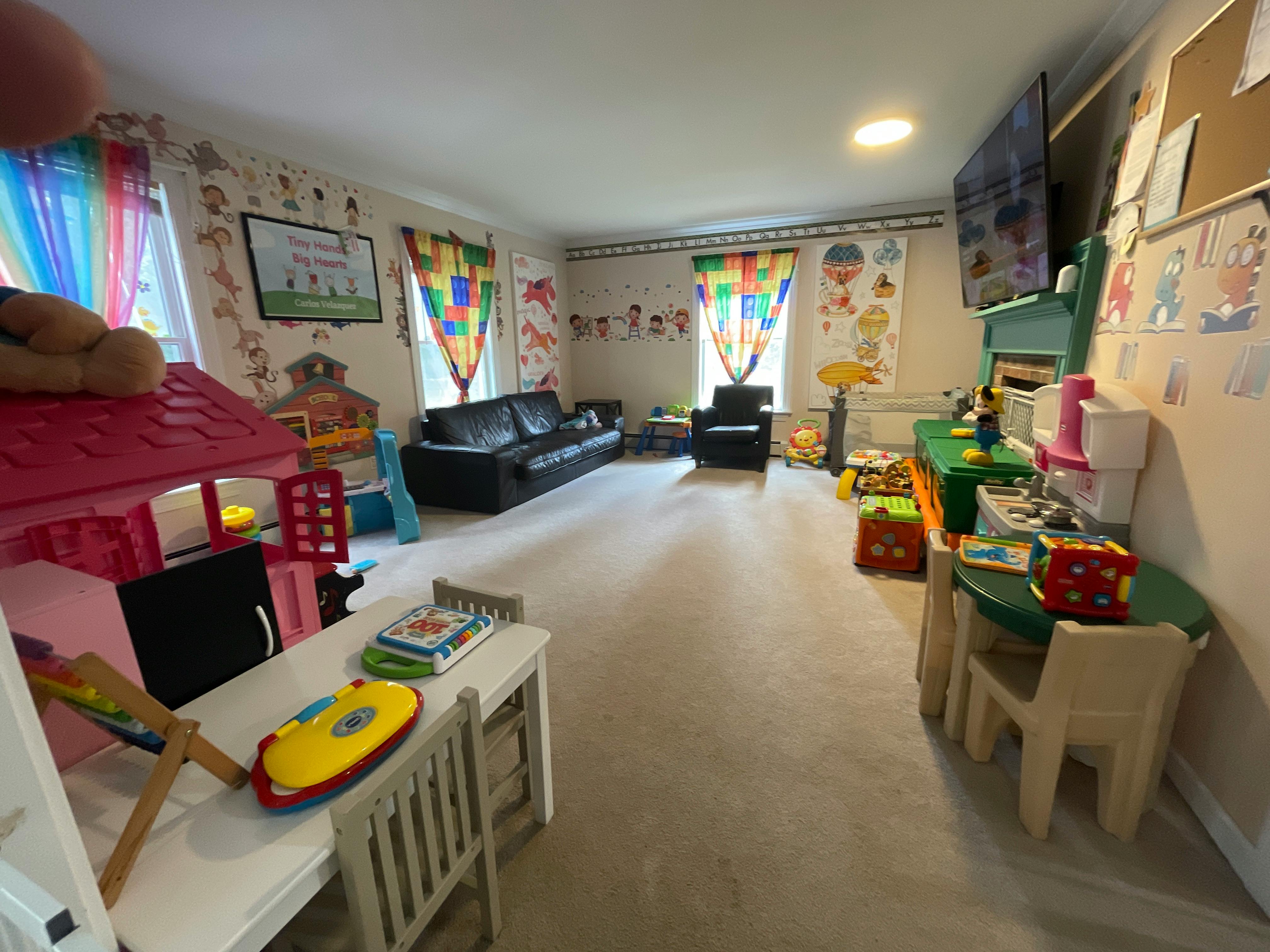 Playroom with toys, small tables, and a black sofa